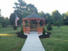 Amish 12 Foot Wood Gazebo-In-A-Box with a pathway and flag