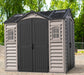 A beige and gray Duramax Apex Pro 10.5'x8' storage shed with double doors and multiple windows.