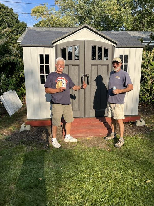 Two men standing in front of an installed Lifetime 10x8 ft. storage shed in a backyard.