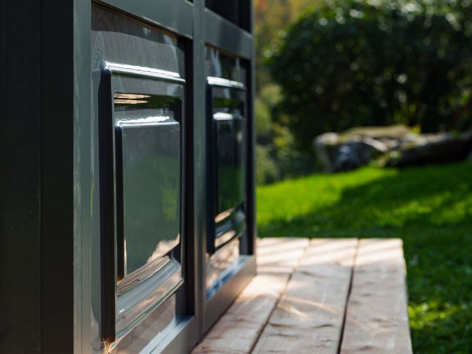 Side view of the 12x12 gazebo's sliding window mechanism, focusing on the ventilation gap and the robust frame, set against a blurred garden background.