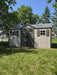 Lifetime 15x8 ft. storage shed installed in a grassy yard, front angle view with closed doors.