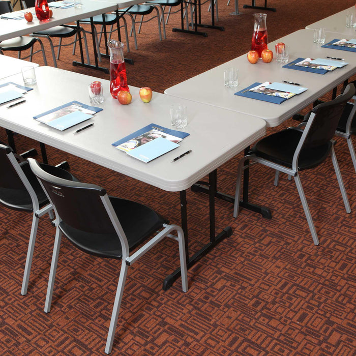 Close view of Lifetime 18 Pack Professional Folding Table 6 ft with notebooks, pens, glasses, and beverage pitcher