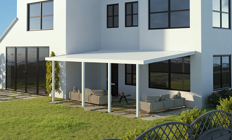 The Four Seasons Outdoor Living Solutions Optima Patio Cover attached in front. The patio cover has a white aluminum frame and a solid white roof. There are four posts supporting the cover.