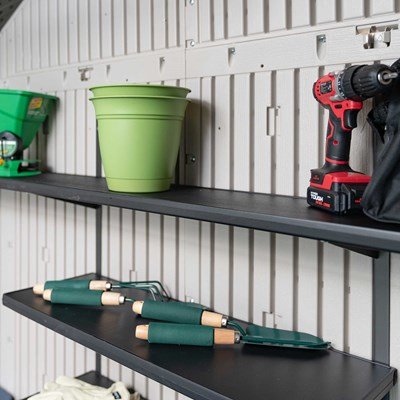 Close-up of the Lifetime storage shed's interior shelf with a plant pot, drill, and garden tools.