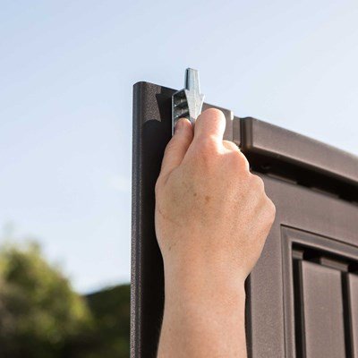 Close-up of a hand installing the Lifetime storage shed's steel door hinge pin.