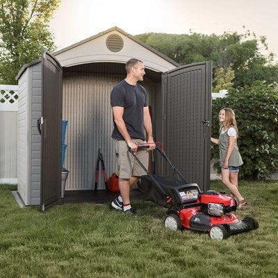 Man and daughter with a lawn mower next to the Lifetime 8x5 ft. storage shed with open doors.