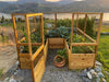 A front view of the Outdoor Living Today Garden in a Box 8×8 with deer fence its gate open, revealing lush vegetable plants growing inside.