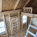 Interior of 9x8 Pennfield Cottage Playhouse highlighting loft area with wooden ladder, heart-shaped Dutch door, and natural OSB wall panels.