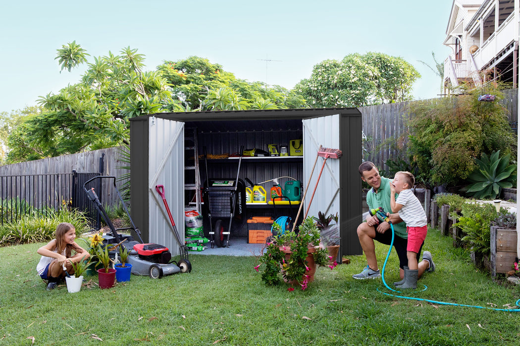 Family gathered around the opened Absco Premier 10' Metal Shed with tools inside, placed in a backyard.
