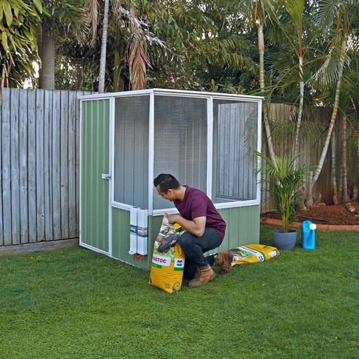 5x5ft Absco Chicken Coop with man outside holding a yellow sack.