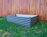 Empty Absco 6' x 3' The Organic Garden Co Metal Rectangle Garden Bed from an angled perspective set on a grassy background.