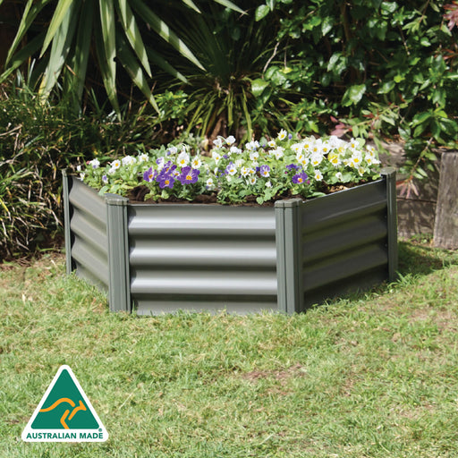 The Absco Organic Garden Co 3.28' x 3.28' Metal Hex Garden Bed with flowers in a backyard setting.