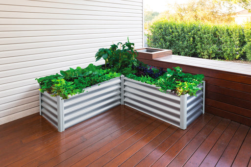 The Absco Organic Garden Bed 4' x 4' x 1.3' filled with plants on a wooden deck.