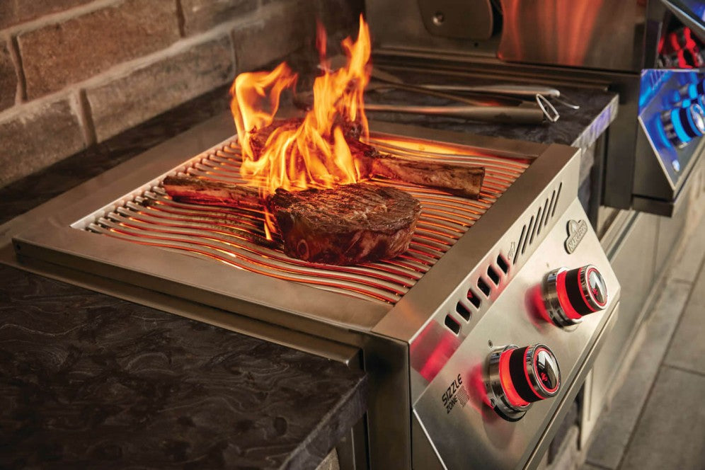 The Napoleon Grills Burner showcasing the grilling space with steaks being cooked among high, fiery flames.