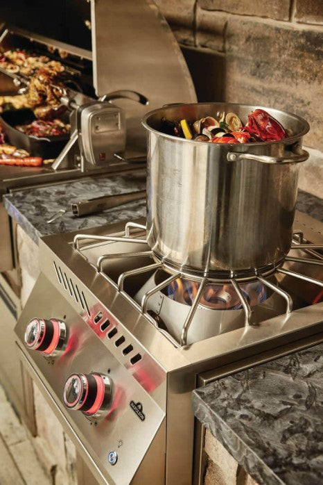 A full view of the Napoleon Grills Burner with a large pot on the burner and an assortment of grilled foods in the background.
