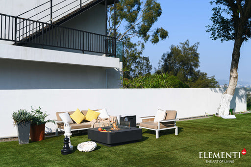 A cozy lawn setting featuring a couch, table, and chairs, highlighted by the warm flames of a Bergamo Fire Table