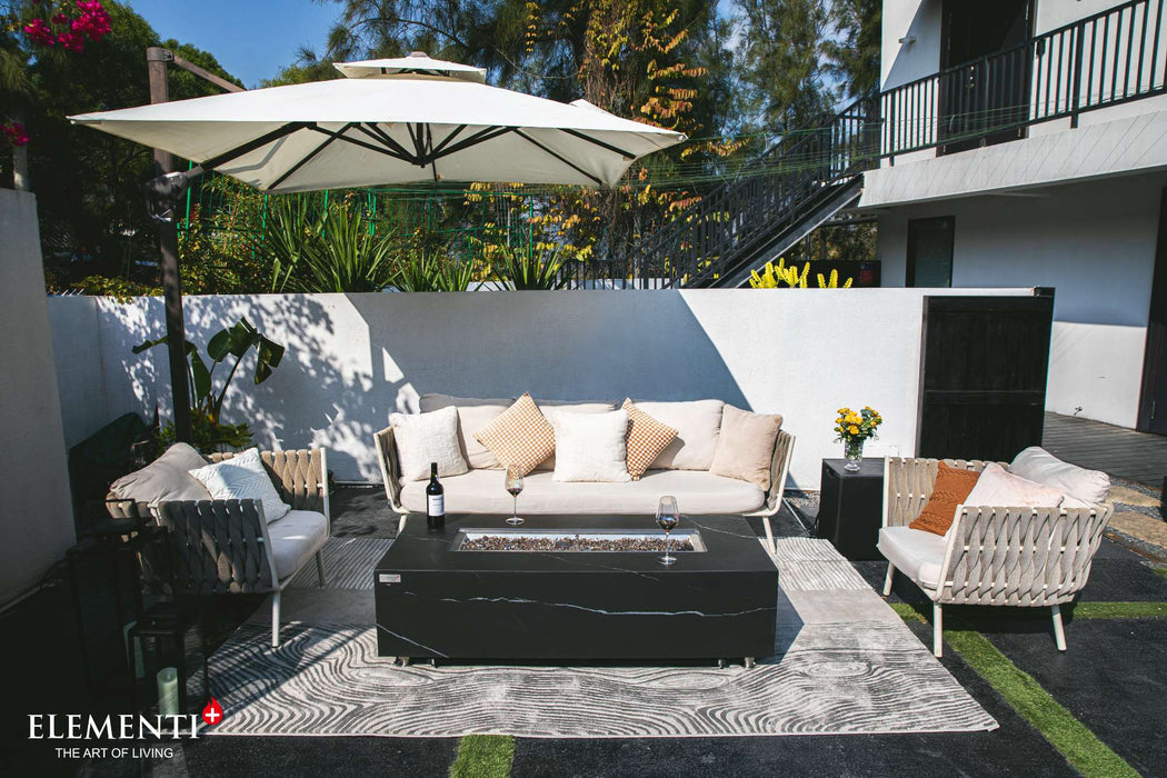 A patio featuring wicker furniture and an umbrella, complemented by a Bulgaria Black Varna Marble Porcelain Fire Table