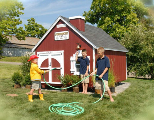 Three boys playing in the garden outside The Firehouse Playhouse by Little Cottage Company.