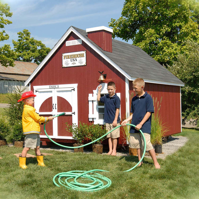 Three boys playing in the garden outside The Firehouse Playhouse by Little Cottage Company.