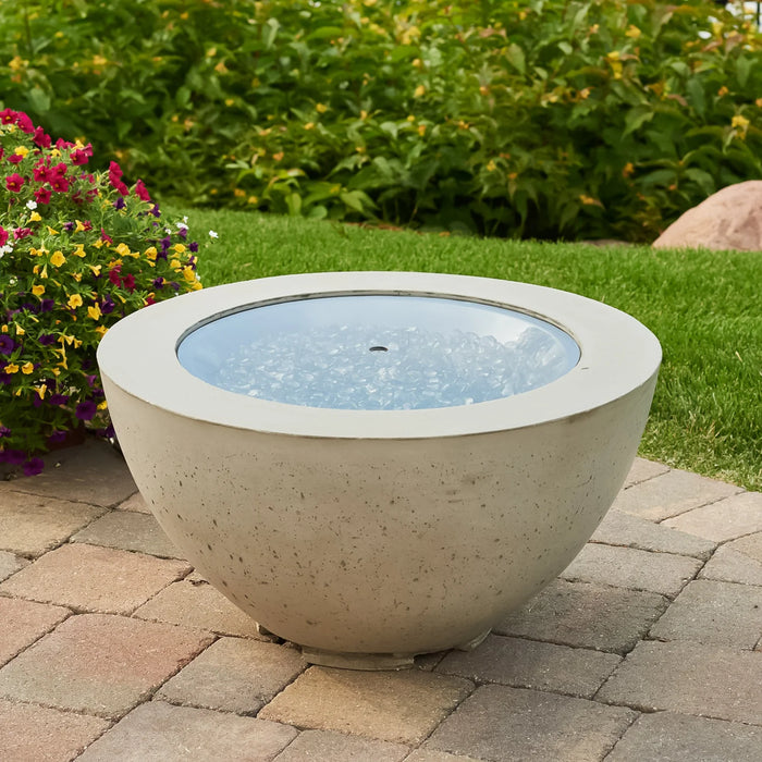 The Outdoor Greatroom Co Cove Round 29-inch gas fire pit bowl, filled with glass gems, not ignited, on a paver patio.