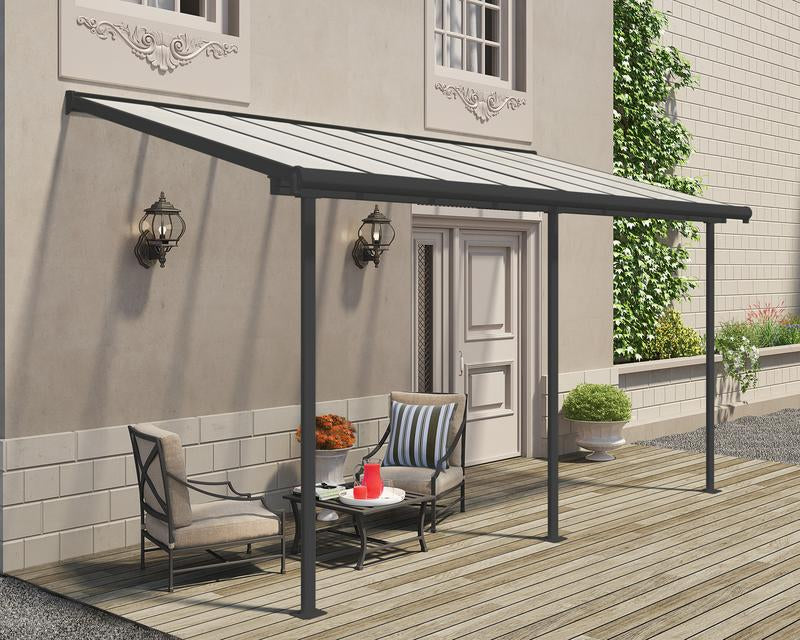 Outdoor lifestyle setting featuring Canopia Sierra 7.5' x 15' Patio Cover - Grey/Clear, shading a patio seating area by a home.