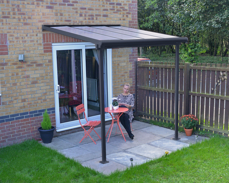 Outdoor lifestyle setting featuring Canopia Sierra 7' x 7' Patio Cover - Grey/Clear, shading a cozy seating area by a home.