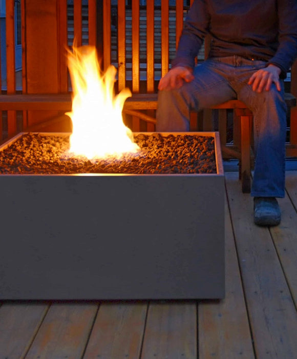 Evening descends on a Solus Decor Firebox 30, casting a warm glow over a comfortable outdoor deck seating area.