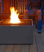 Evening descends on a Solus Decor Firebox 30, casting a warm glow over a comfortable outdoor deck seating area.