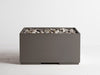 Cinder grey Solus Decor Firebox 30 featuring a minimalist cubic structure filled with natural pebbles for an elegant outdoor ambience.