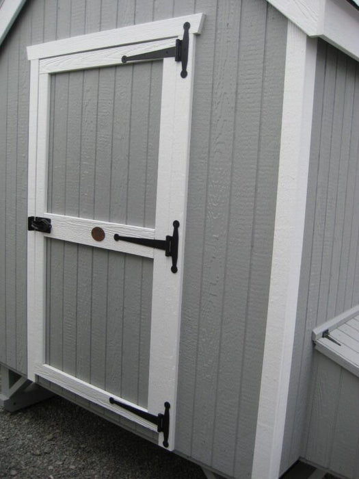 Close-up of the sturdy door design on the Little Cottage Company Colonial Gable Chicken Coop, featuring black hardware and white trim.