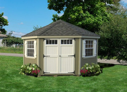 The Colonial Five-Corner Shed by Little Cottage Company, displaying a charming outdoor setting with beige walls, white trim, and vibrant flower accents.
