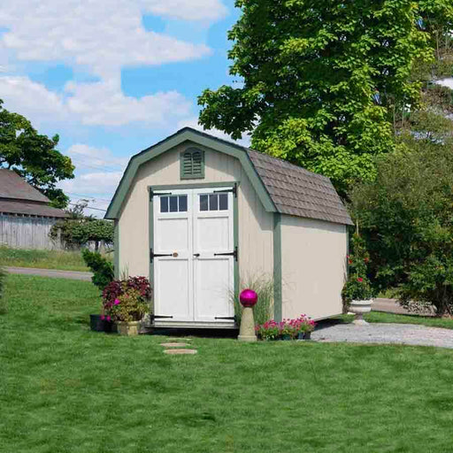 A quaint Colonial Greenfield Shed by Little Cottage Company alongside a garden path with flowering plants.