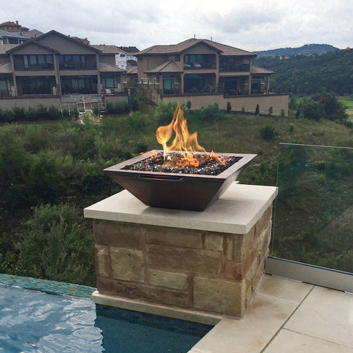 Luxurious outdoor setting featuring a square Maya fire and water bowl in hammered copper, overlooking a scenic landscape.