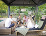 Four white people talking and drinking besides a pool while sitting in lounge chairs under the Canopia Dallas Gazebo