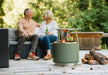 Bonfire Fire Pit plus Stand 2.0 placed outdoors with couple in the background.