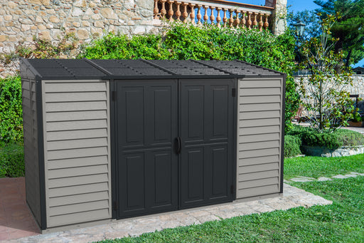 Duramax Sidemate Plus 10x4 Vinyl  Storage Shed - Grey and Beige, nestled against a stone wall in a sunlit backyard with lush greenery and a cobblestone pathway.