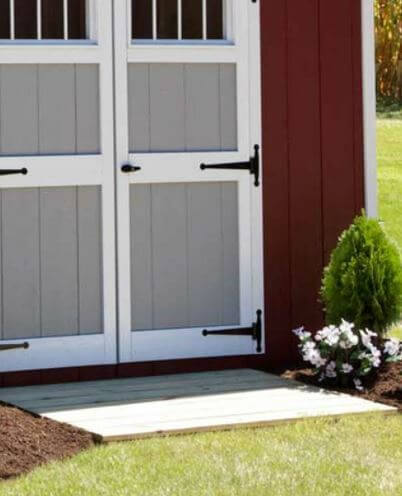 Close-Up of EZ-Fit Sheds Craftsman Storage Shed Double Doors with Red and Gray Panel Design, Surrounded by Greenery