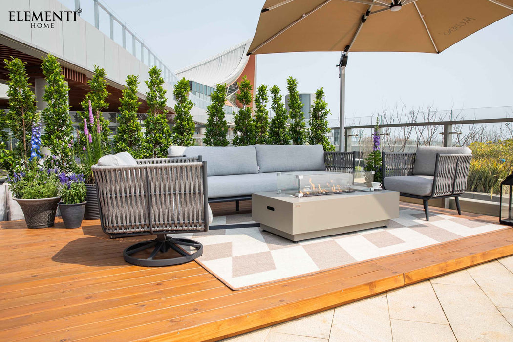 A complete patio setup featuring Elementi Outdoor Furnitures Milano Collection, including a sofa, chairs, and a fire pit under an umbrella.