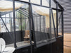 The Exaco Janssens Modern Greenhouse with a unique push-out side window feature, offering fresh air circulation for a healthy plant environment, set against an urban backdrop.