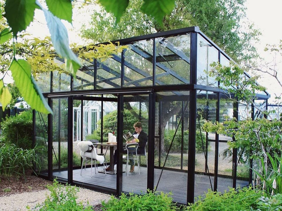 Exaco Janssens modern greenhouse with a sloped roof situated in a lush yard, perfect for a relaxing retreat or a passionate gardener’s sanctuary.