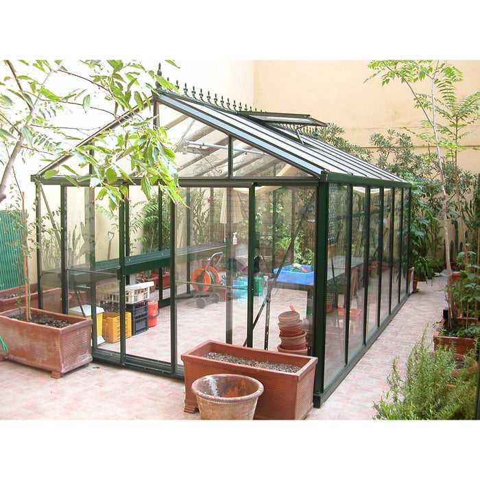 An Exaco Janssens Royal Victorian VI 46 Greenhouse nestled in a cozy courtyard, brimming with potted plants and terracotta accents, exuding a Mediterranean charm.