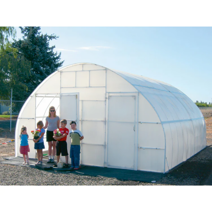 Family with young children standing in front of a Solexx Conservatory Deluxe greenhouse, each holding colorful flower pots