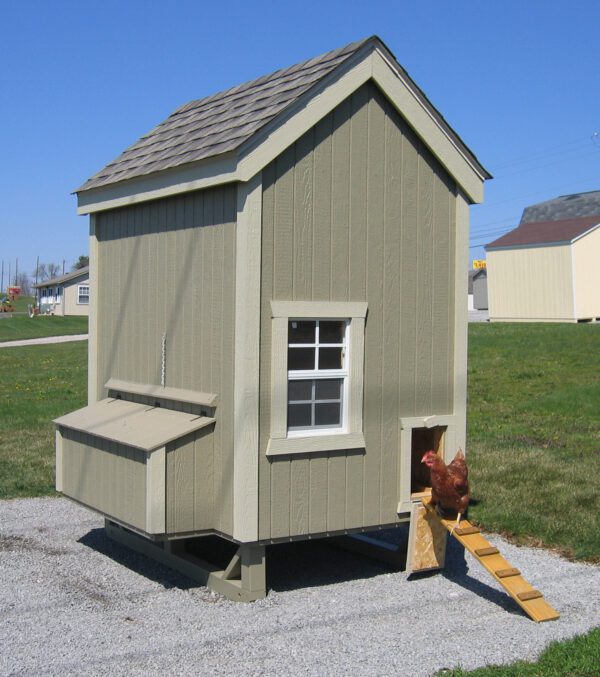 A quaint Colonial Gable Chicken Coop from Little Cottage Company, featuring a sage green exterior with white accents and a chicken ramp.