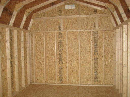 The interior structure of the Little Cottage Company's Gambrel Barn showing wooden framing and floor kit installation.