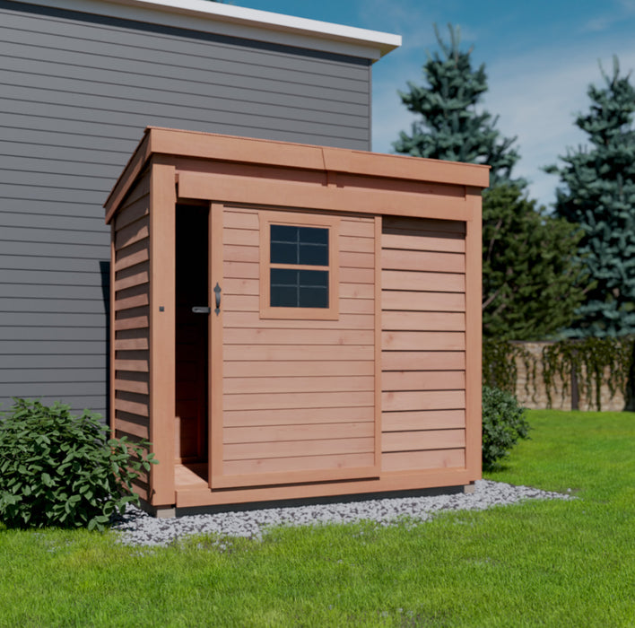 The Outdoor Living Today 8x4 GardenSaver features sliding door that is partially open, providing a glimpse of the interior. The shed is positioned on a grassy lawn beside a stone pathway, under a clear sky. Tall green trees surround the area, creating a serene outdoor setting.