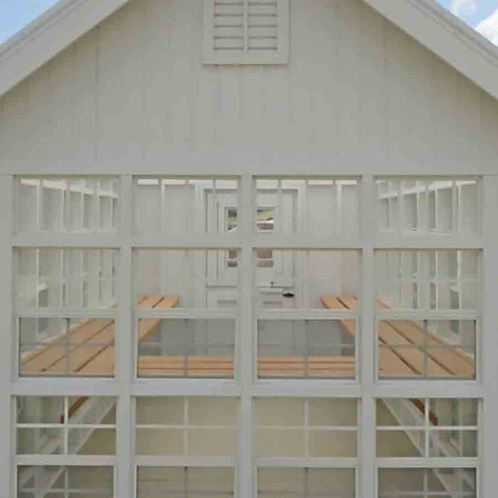 Front view of a Little Cottage Company Gable Greenhouse featuring large windows and a sturdy door.