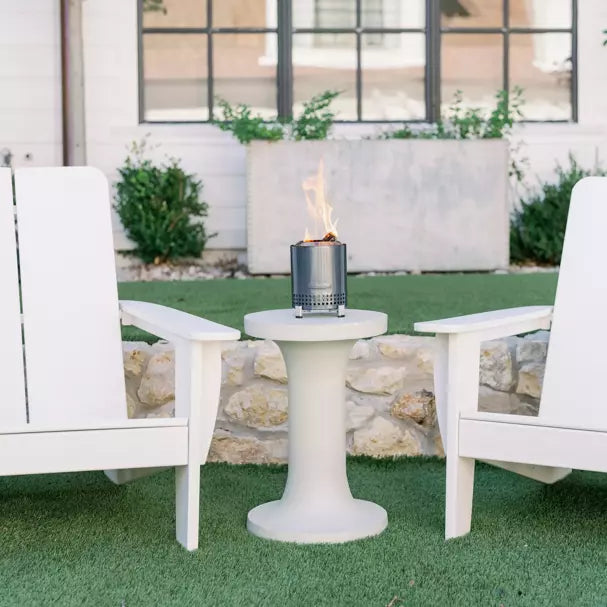 Mesa Fire Pit XL in Gunmetal color placed outdoors on top of table with chairs beside.