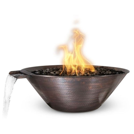 A 31-inch Remi round hammered copper bowl from The Outdoor Plus, beautifully combining a water feature with a central fire element on a bed of lava rocks in white background