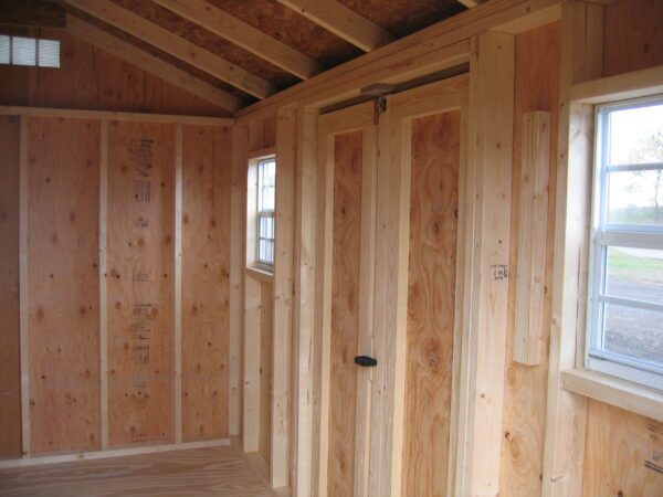 Interior view of the Classic Garden Workshop Shed showing natural wooden walls and framing with ample light from a side window, ready for customization.
