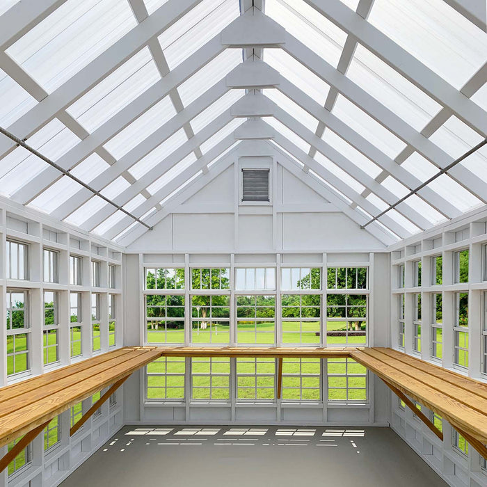 Interior of Little Cottage Company's Gable Greenhouse with wooden shelves and ample natural light.
